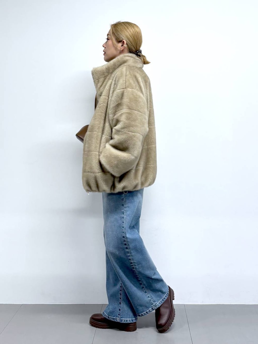 ブルー系のデニムパンツ、ブラウン系のニット/セーター、ブラウン系のショルダーバッグを着用したレディースの秋コーディネートの2枚目の写真