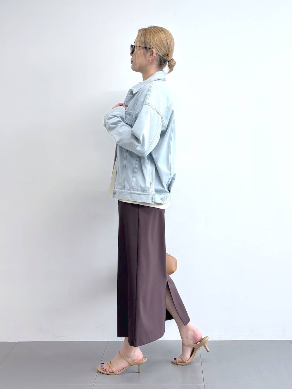 ブルー系のデニムジャケット、ブラウン系のスカート、ブラウン系のサングラスを着用したレディースの冬コーディネートの3枚目の写真