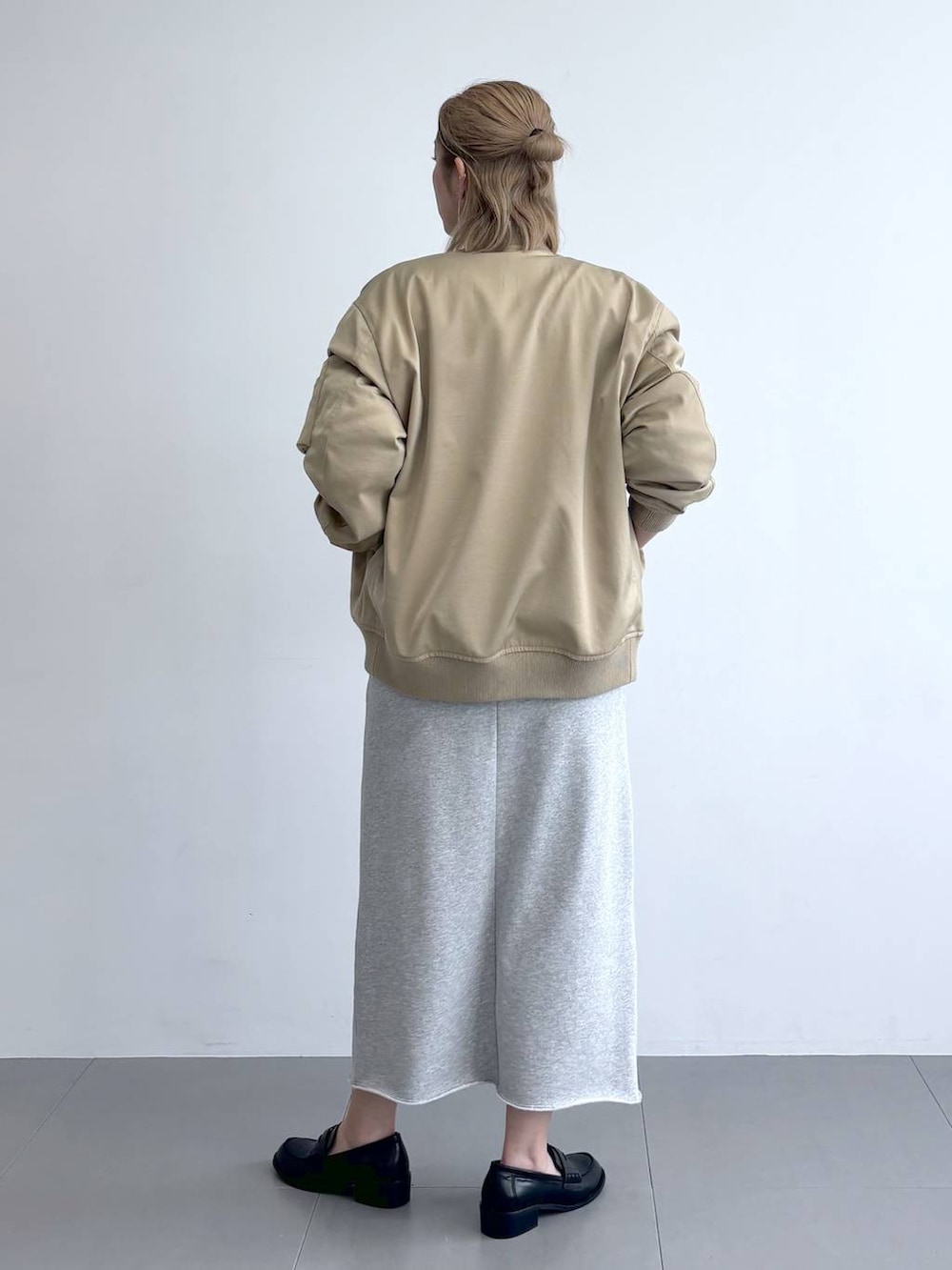 ブラック系のニット/セーター、ベージュ系のMA-1、グレー系のスカートを着用したレディースの冬コーディネートの3枚目の写真