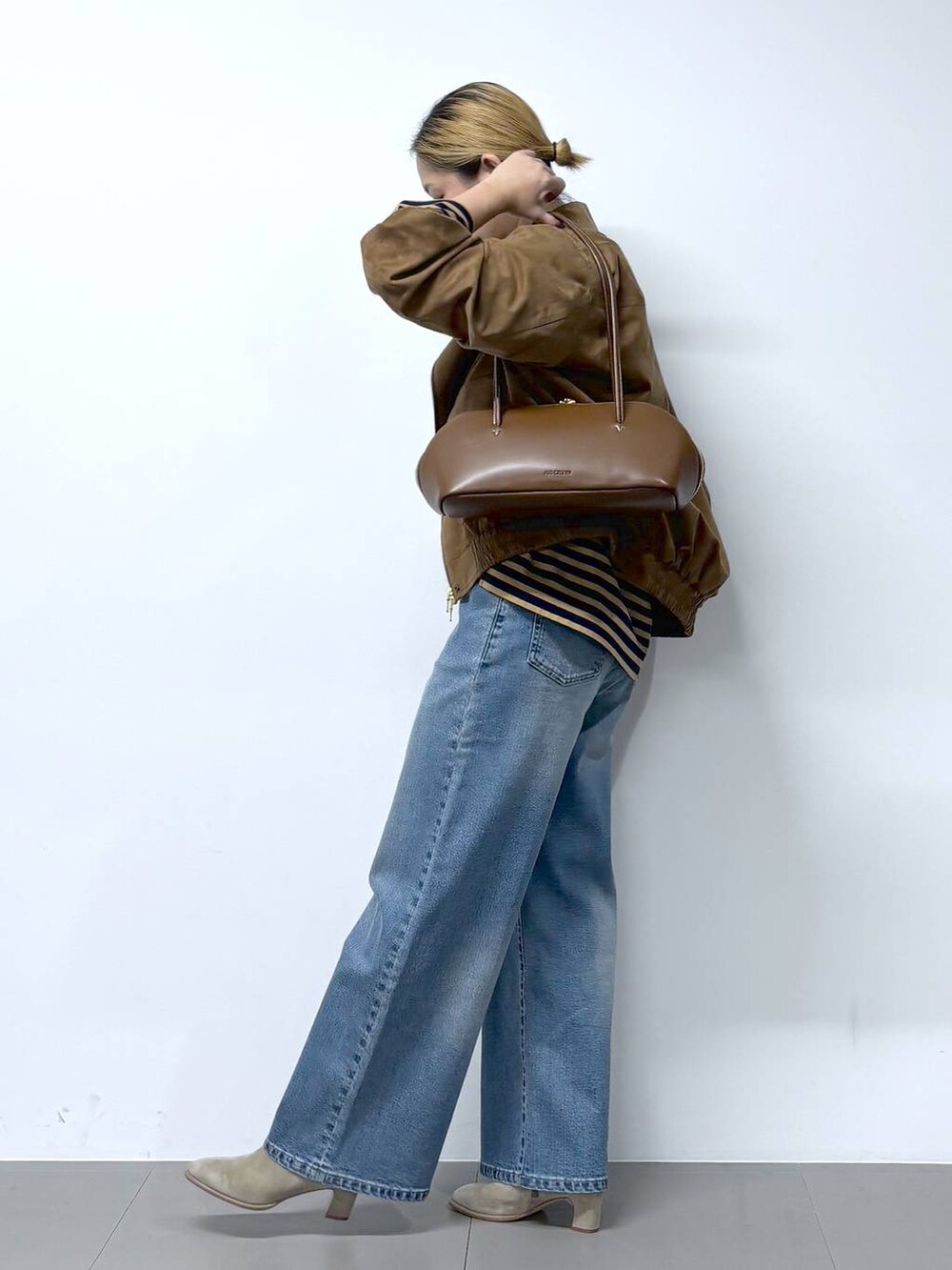 ブルー系のデニムパンツ、ブラウン系のトートバッグ、ベージュ系のTシャツ/カットソーを着用したレディースの秋コーディネートの4枚目の写真