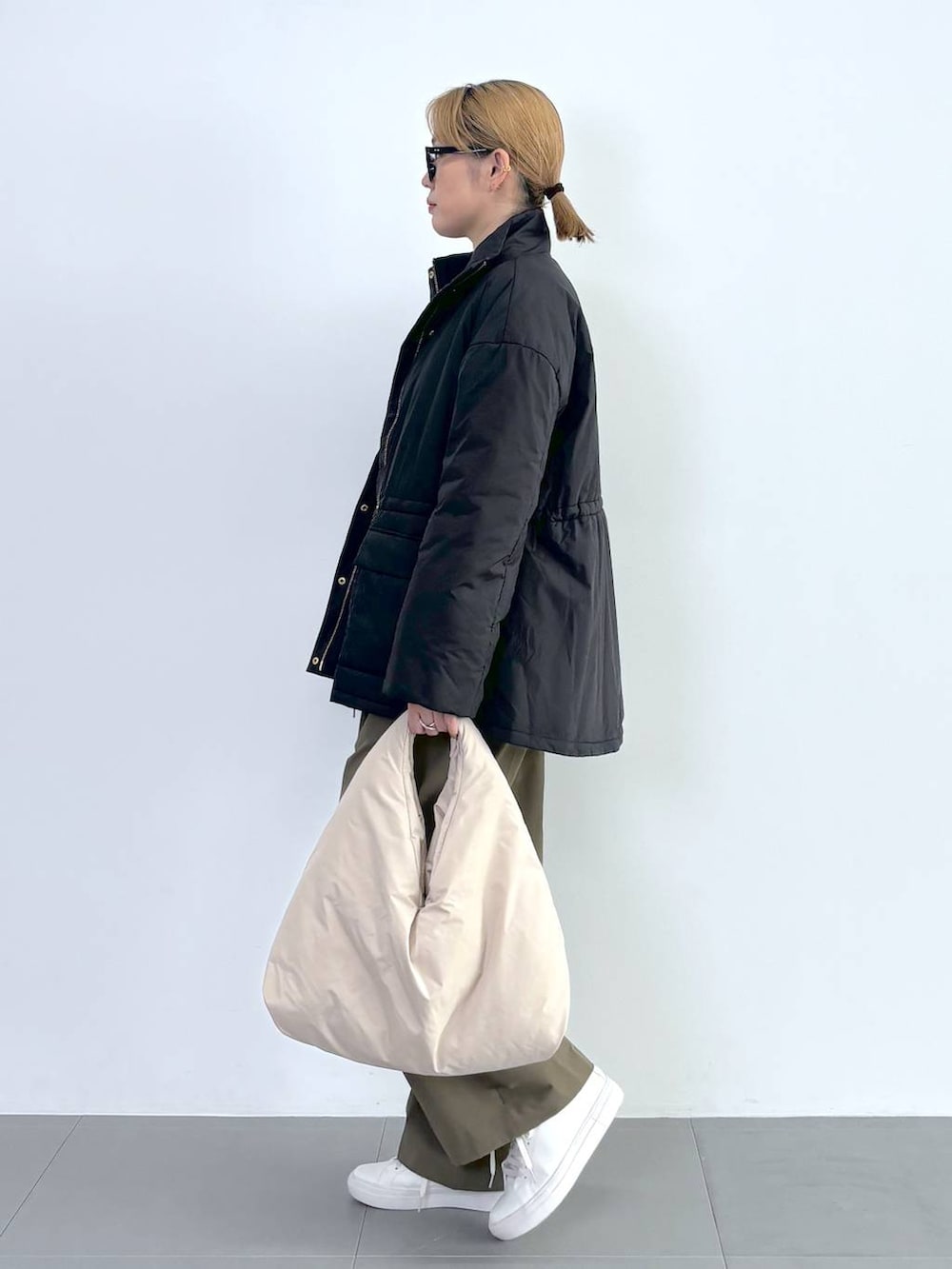 ブラック系のブルゾン、ホワイト系のスニーカー、グレー系のニット/セーターを着用したレディースの秋コーディネートの3枚目の写真