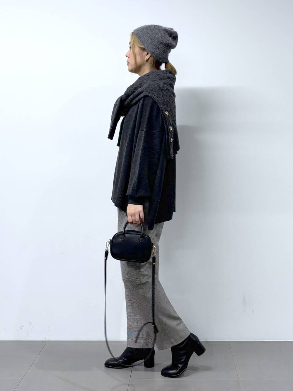 ブラック系のショルダーバッグ、ブラック系のブーツ、グレー系のニット/セーターを着用したレディースの秋コーディネートの2枚目の写真