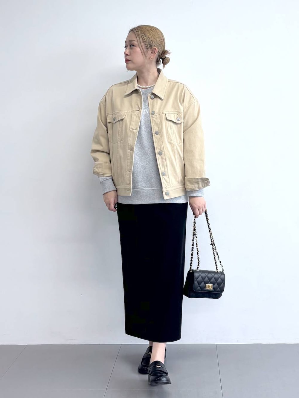 ベージュ系のデニムジャケット、グレー系のスウェット、ブラック系のスカートを着用したレディースの冬コーディネートの2枚目の写真