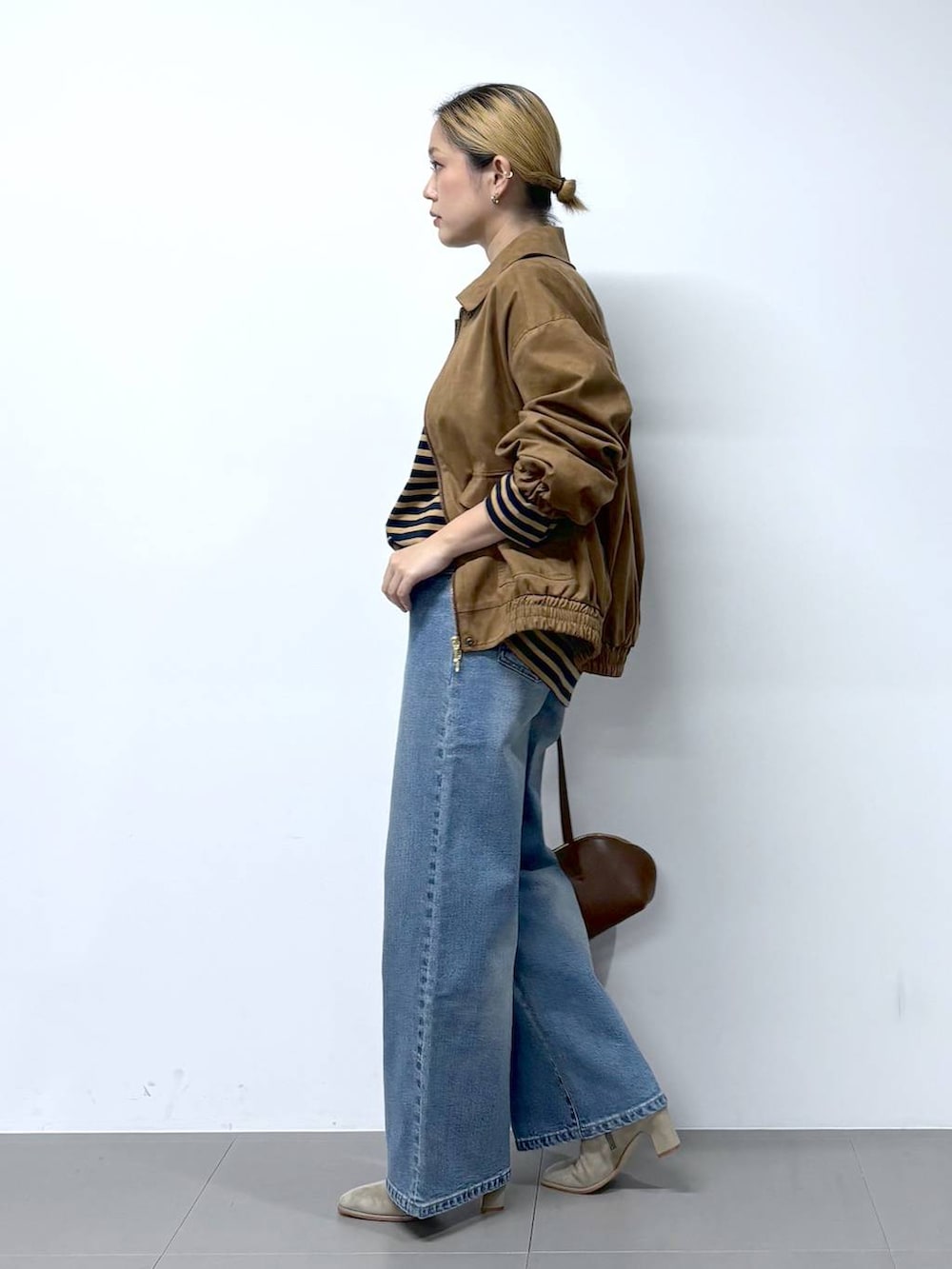 ブルー系のデニムパンツ、ブラウン系のトートバッグ、ベージュ系のTシャツ/カットソーを着用したレディースの秋コーディネートの5枚目の写真