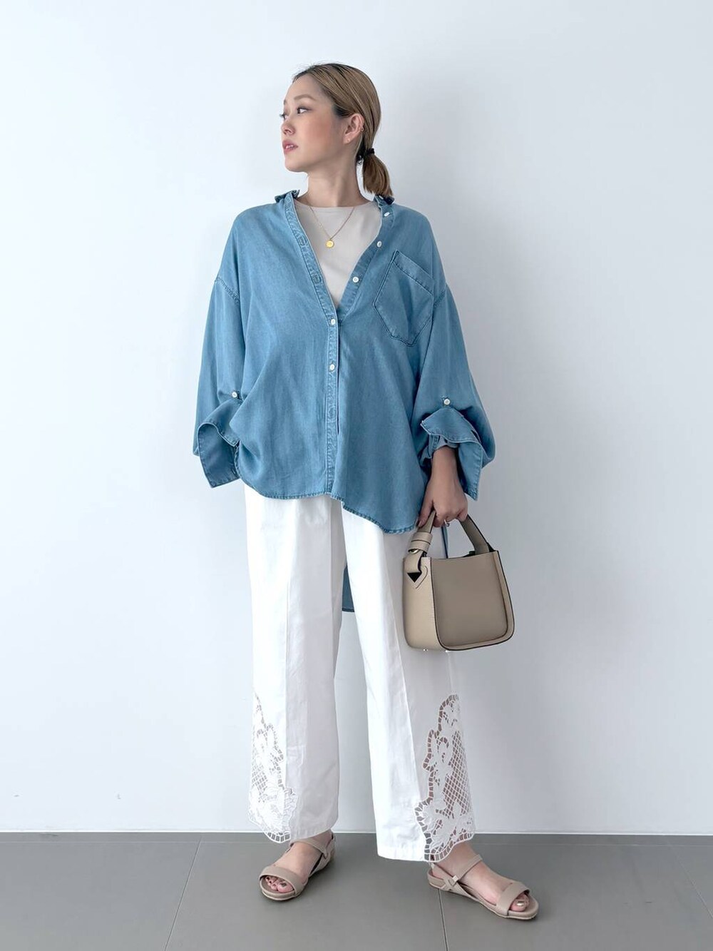 ブラウン系のハンドバッグ、ベージュ系のサンダル、ブルー系のシャツ/ブラウスを着用したレディースの夏コーディネートの2枚目の写真