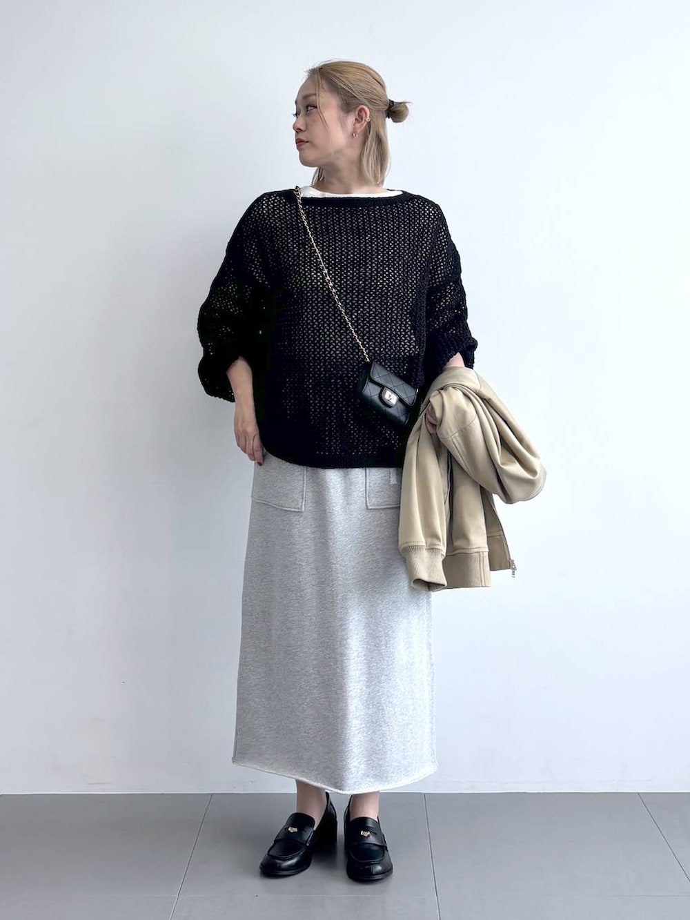 ブラック系のニット/セーター、ベージュ系のMA-1、グレー系のスカートを着用したレディースの冬コーディネートの4枚目の写真