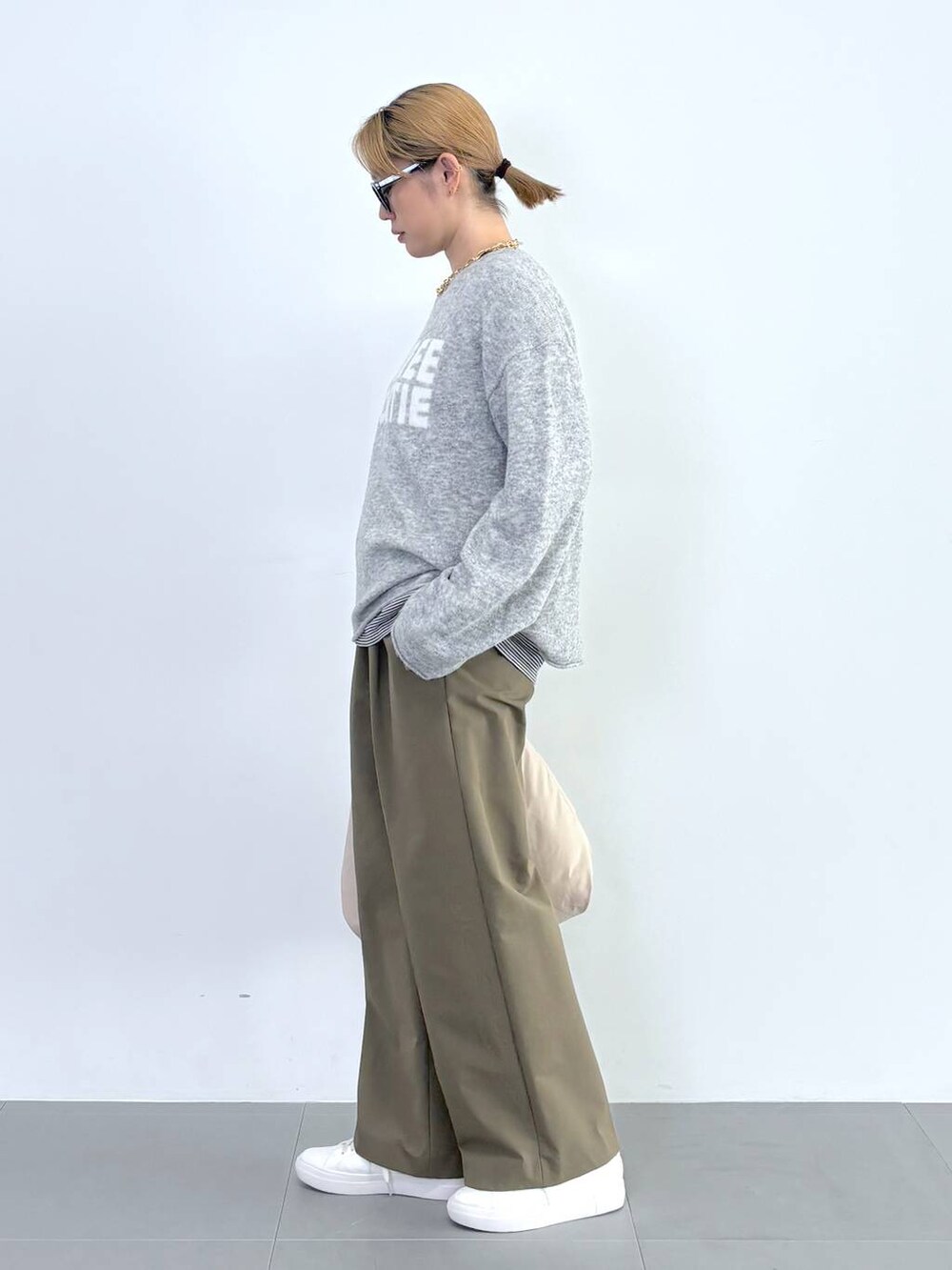 ブラック系のブルゾン、ホワイト系のスニーカー、グレー系のニット/セーターを着用したレディースの秋コーディネートの7枚目の写真