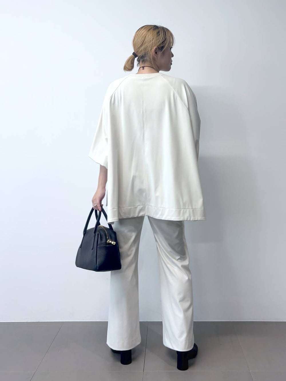 ブラック系のボストンバッグ、ブラック系のその他アウター、ホワイト系のTシャツ/カットソーを着用したレディースの秋コーディネートの9枚目の写真