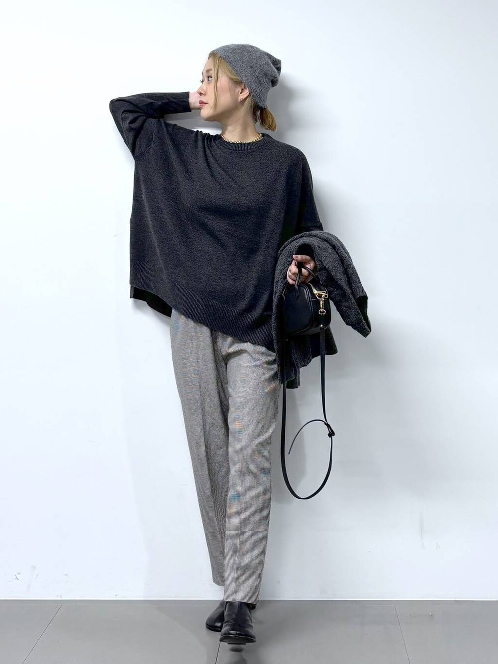 ブラック系のショルダーバッグ、ブラック系のブーツ、グレー系のニット/セーターを着用したレディースの秋コーディネートの3枚目の写真