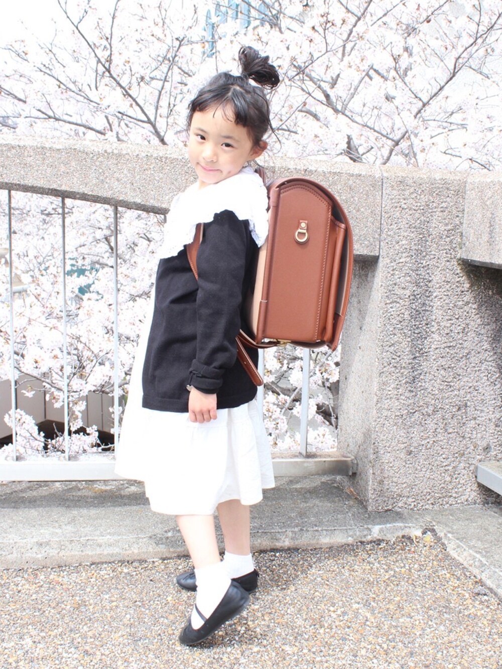 ブラック系のカーディガン/ボレロ、ホワイト系のワンピース、ホワイト系のTシャツ/カットソーを着用したキッズの春コーディネートの3枚目の写真