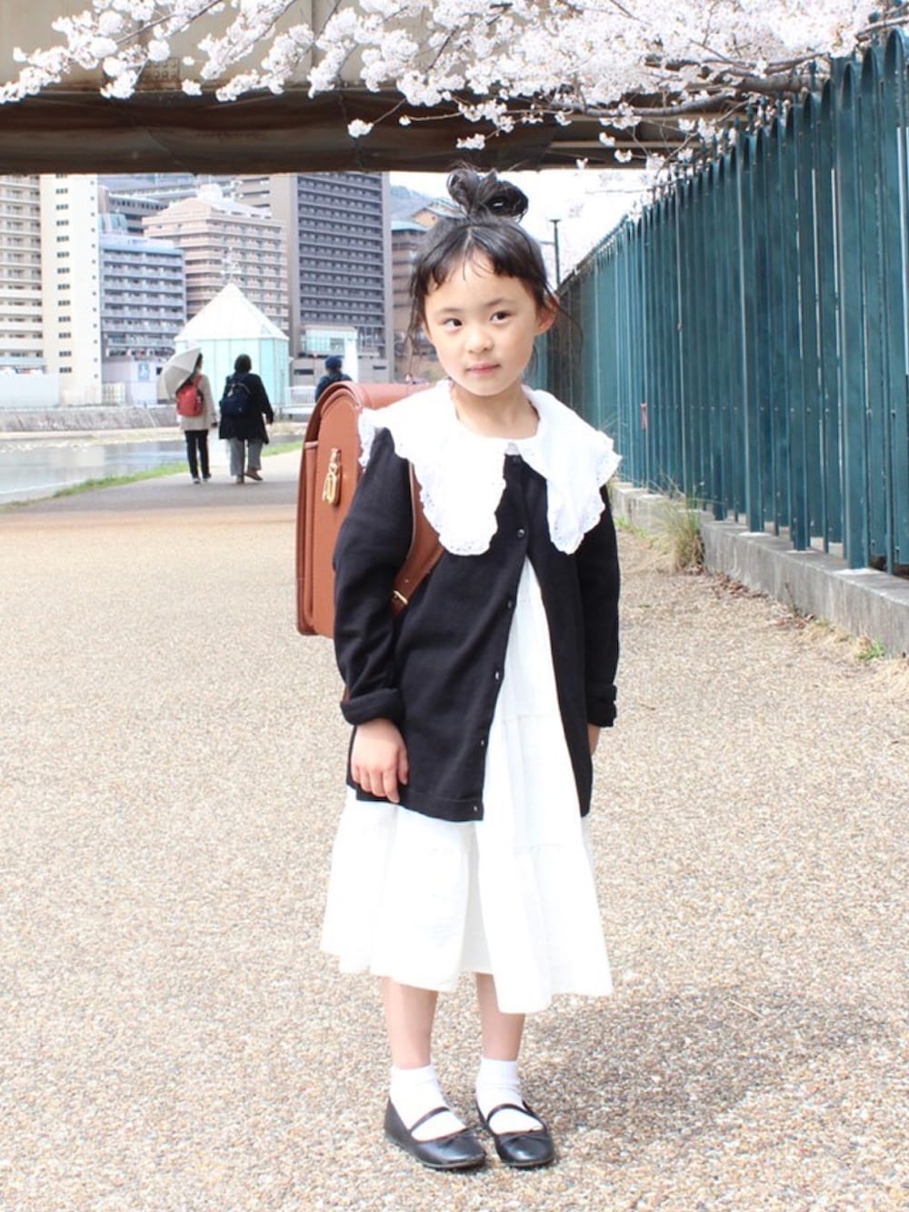 ブラック系のカーディガン/ボレロ、ホワイト系のワンピース、ホワイト系のTシャツ/カットソーを着用したキッズの春コーディネートの2枚目の写真