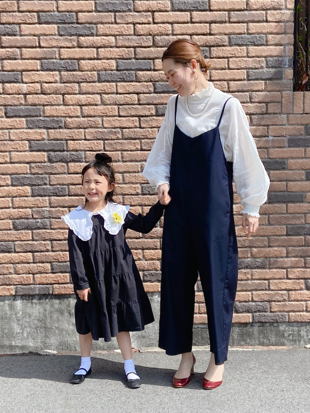 ブルー系のサロペット/オーバーオール、ブラック系のワンピース、ホワイト系のTシャツ/カットソーを着用したキッズの春コーディネートの2枚目の写真