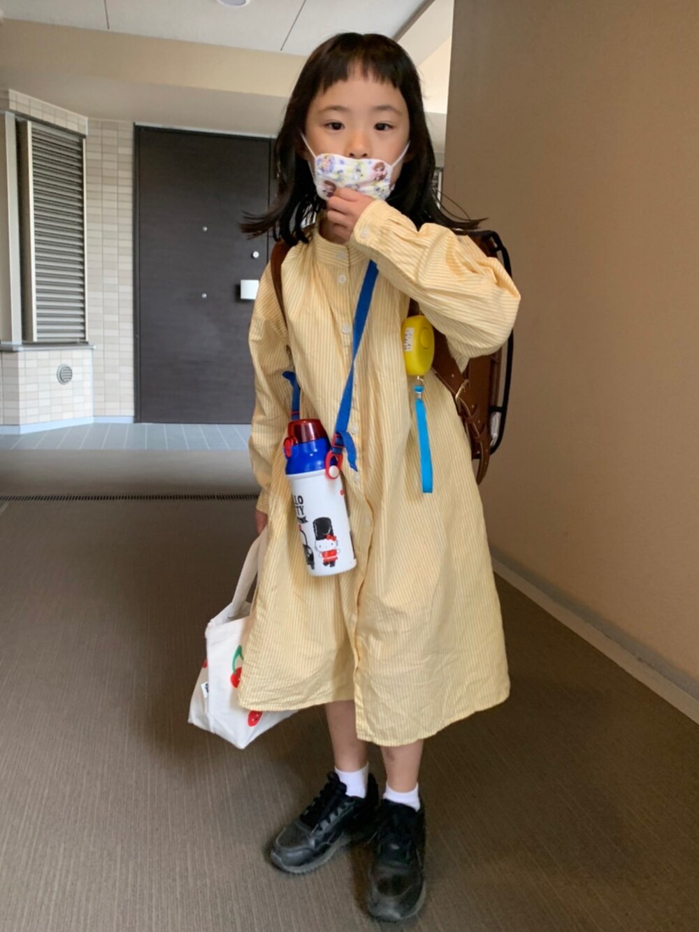 ブラック系のスニーカー、イエロー系のワンピース/ドレスを着用したキッズの春コーディネートの2枚目の写真