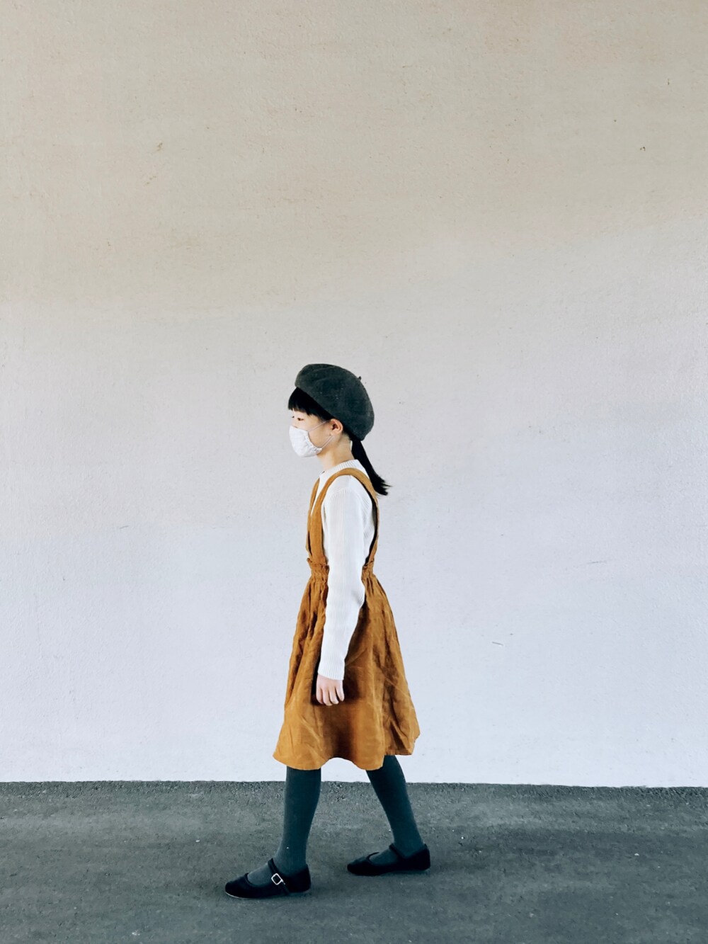 ベージュ系のニット/セーター、ブラウン系のジャンパースカート、ブラック系のバレエシューズを着用したキッズの秋コーディネートの2枚目の写真