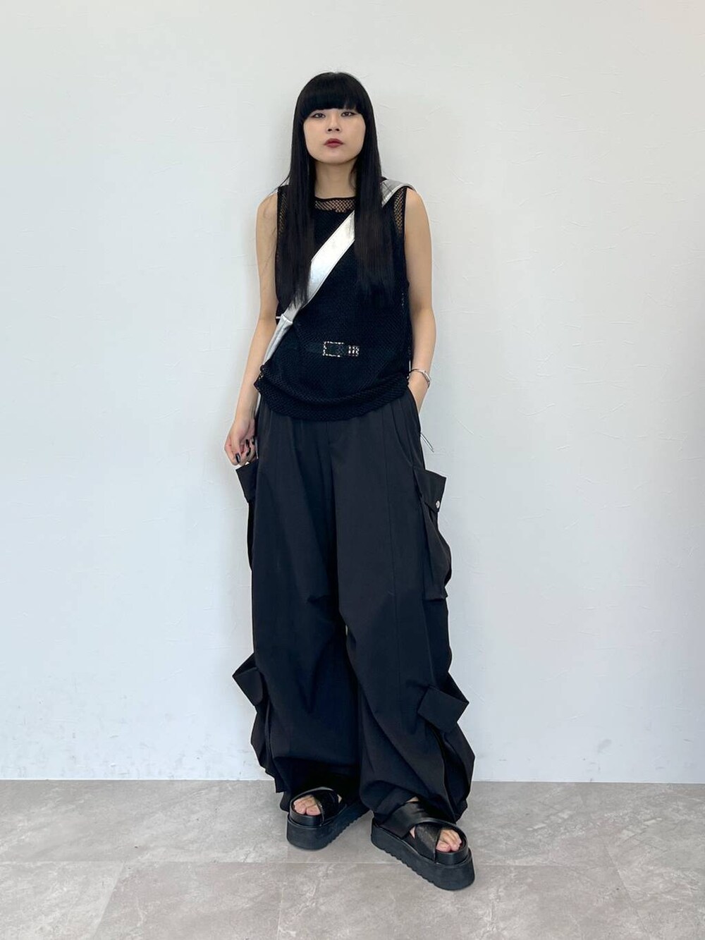 ブラック系のサンダル、シルバー系のショルダーバッグ、ブラック系のスラックスを着用したレディースの夏コーディネートの2枚目の写真