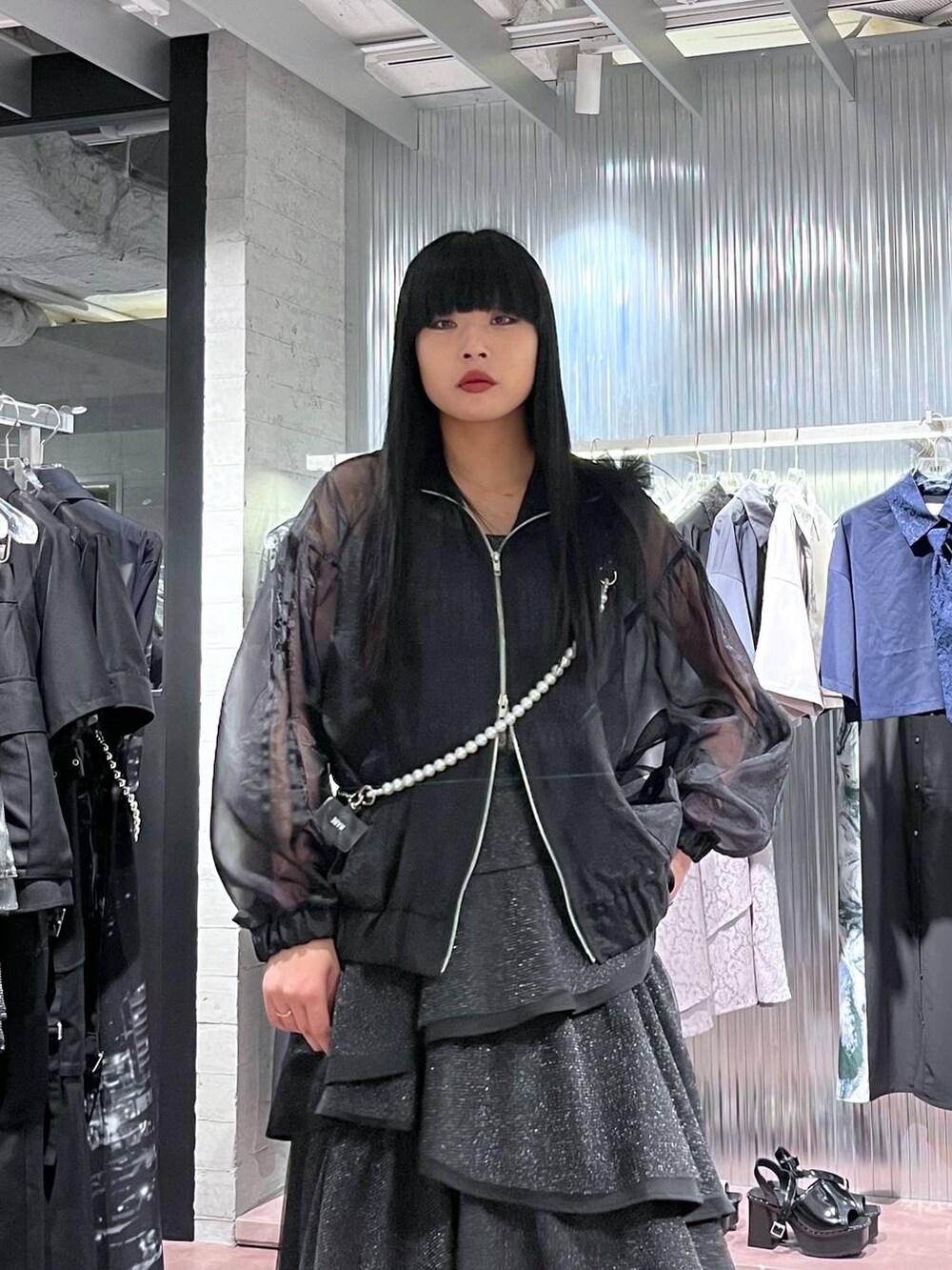 ブラック系のサンダル、ブラック系のスカート、ブラック系のブルゾンを着用したレディースの春コーディネートの5枚目の写真