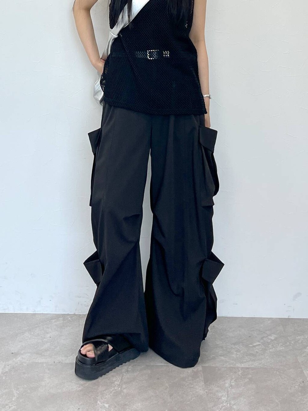 ブラック系のサンダル、シルバー系のショルダーバッグ、ブラック系のスラックスを着用したレディースの夏コーディネートの5枚目の写真