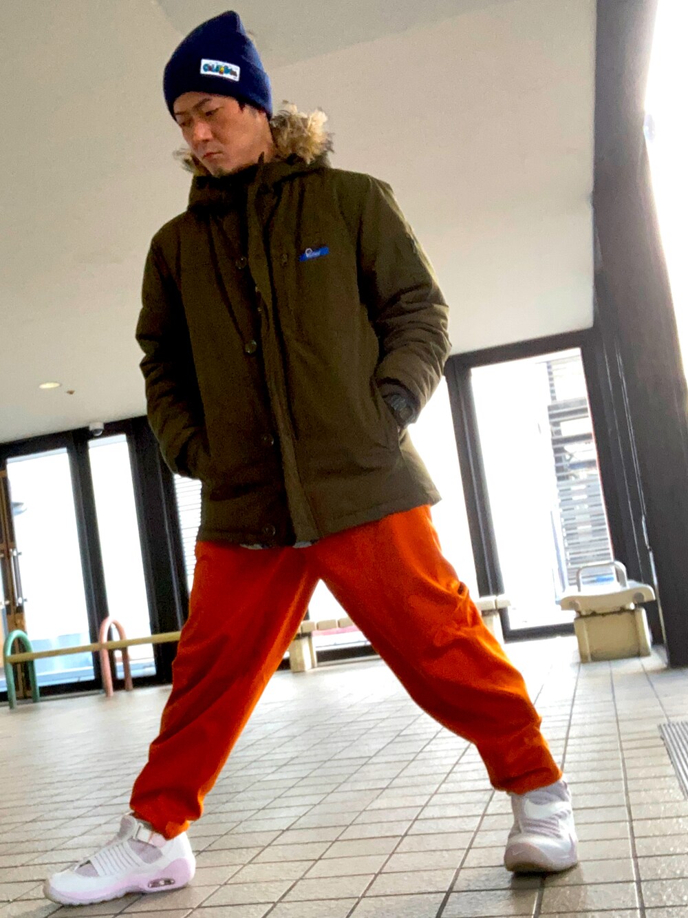 ブルー系のシャツ/ブラウス、グリーン系のミリタリージャケット、オレンジ系のその他パンツを着用したメンズの冬コーディネートの2枚目の写真