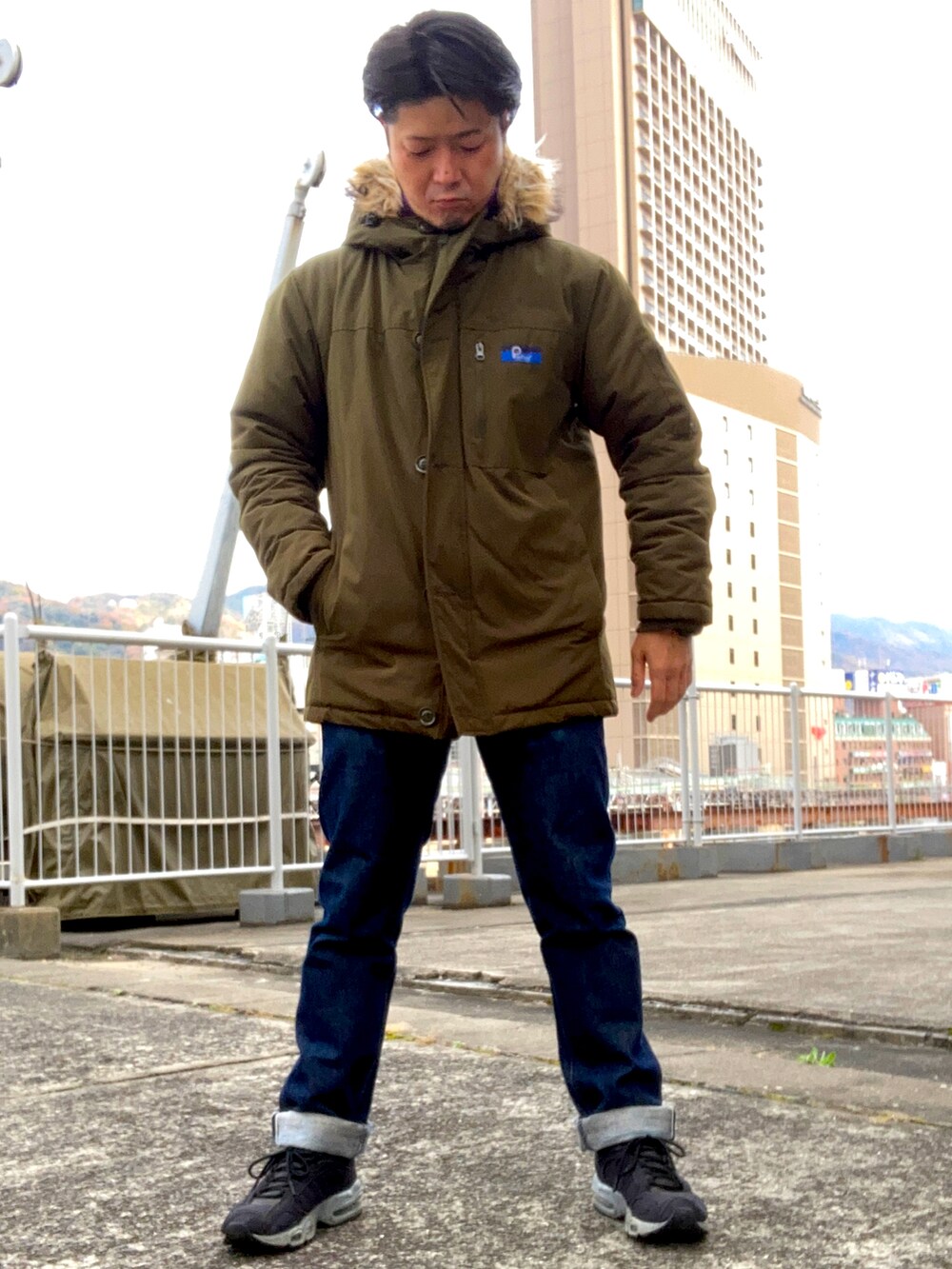 パープル系のその他アウター、グリーン系のミリタリージャケット、ブルー系のデニムパンツを着用したメンズの冬コーディネートの2枚目の写真