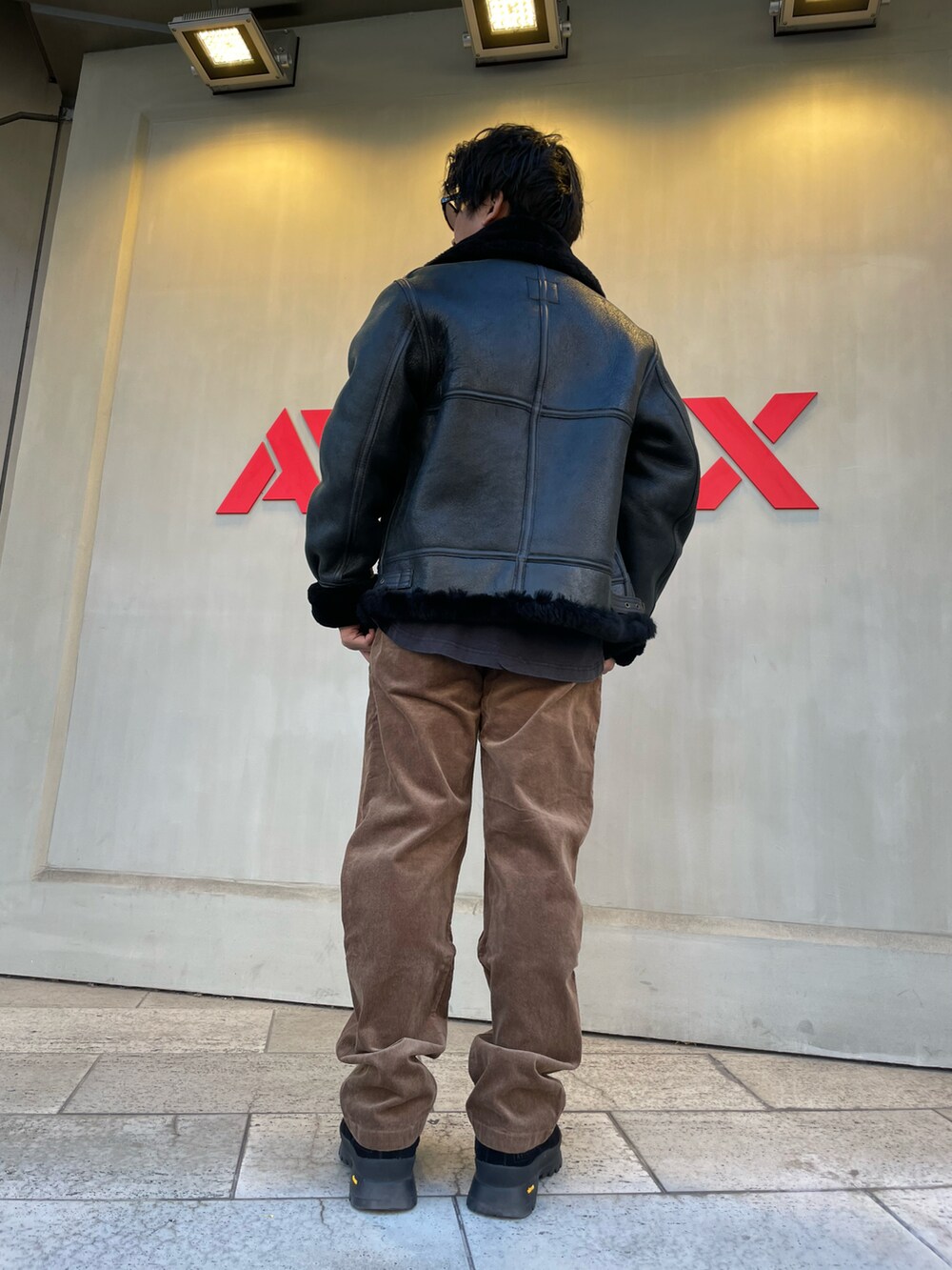 ブラック系のミリタリージャケット、ブラウン系のパンツを着用したメンズの冬コーディネートの2枚目の写真