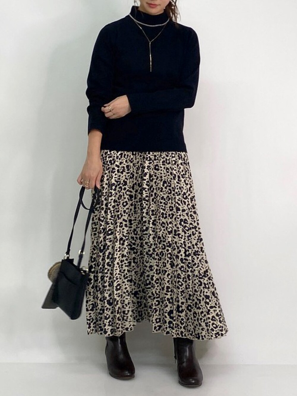 ベージュ系のノーカラーコート、ブラック系のブーツ、ベージュ系のスカートを着用したレディースの冬コーディネートの2枚目の写真