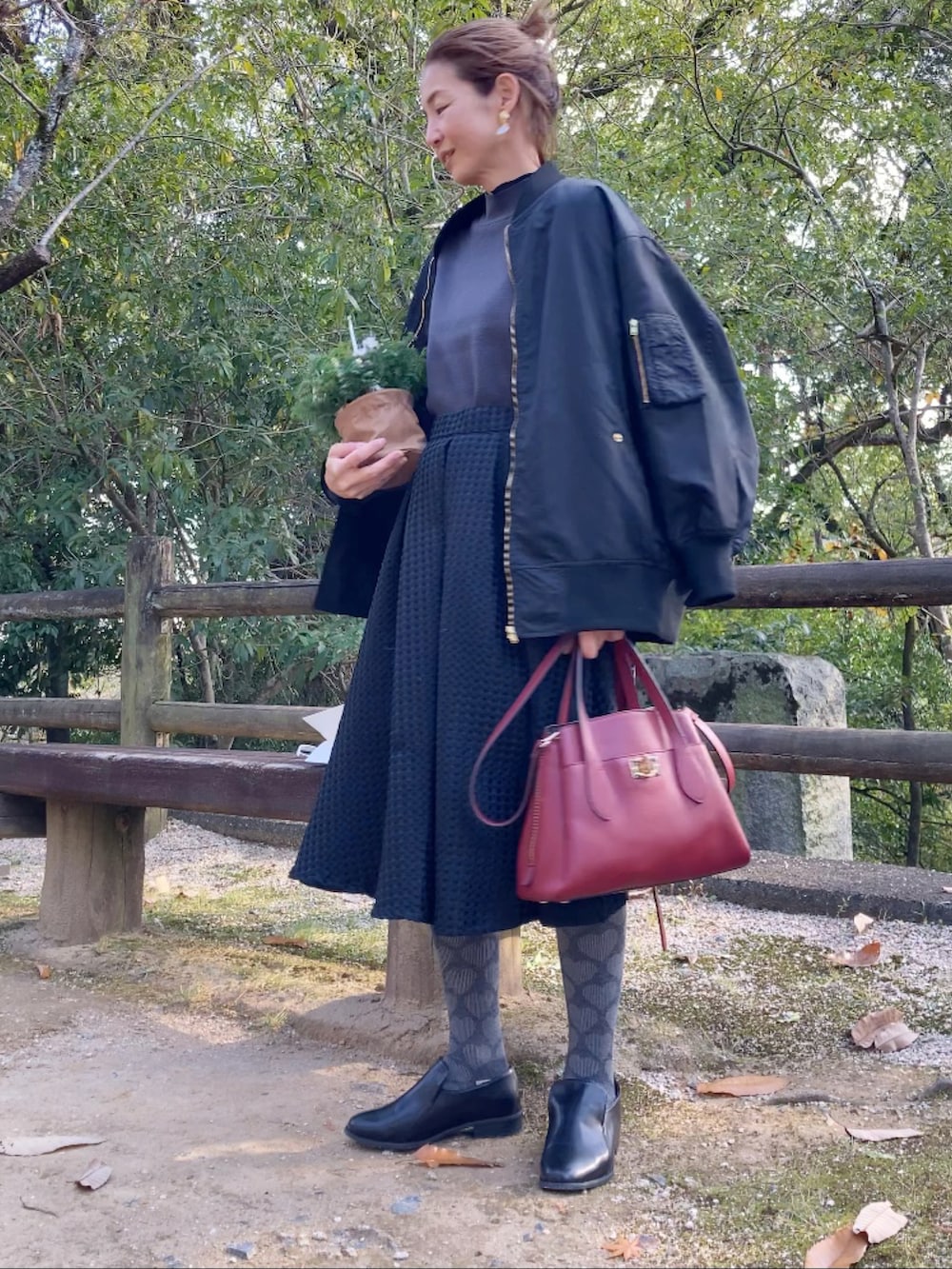 ブラック系のブルゾン、グレー系のニット/セーター、ブラック系のスカートを着用したレディースの冬コーディネートの2枚目の写真