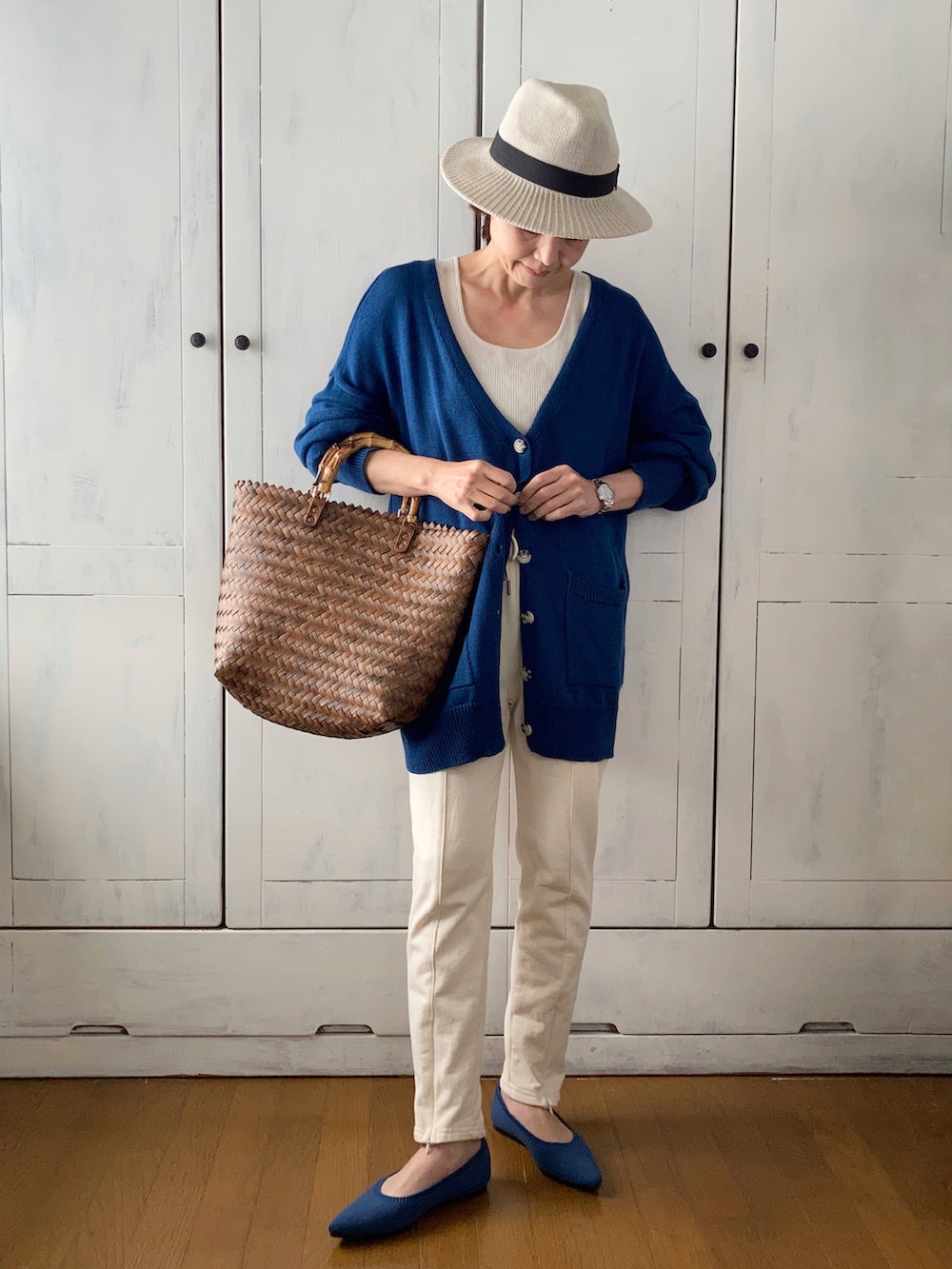 ブルー系のカーディガン/ボレロ、ホワイト系のスウェットパンツ、ブラウン系のかごバッグを着用したレディースの春コーディネートの2枚目の写真