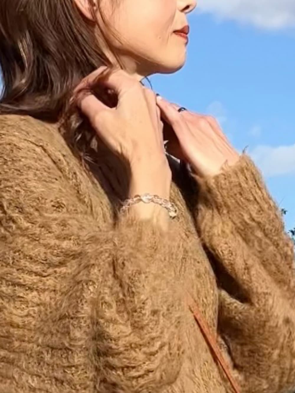 ホワイト系のダウンベスト、ブラウン系のニット/セーター、ホワイト系のスカートを着用したレディースの秋コーディネートの3枚目の写真