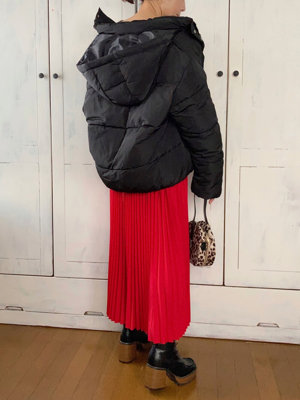 ブラック系のダウンジャケット/コート、ブラウン系のニット/セーター、レッド系のスカートを着用したレディースの冬コーディネートの3枚目の写真