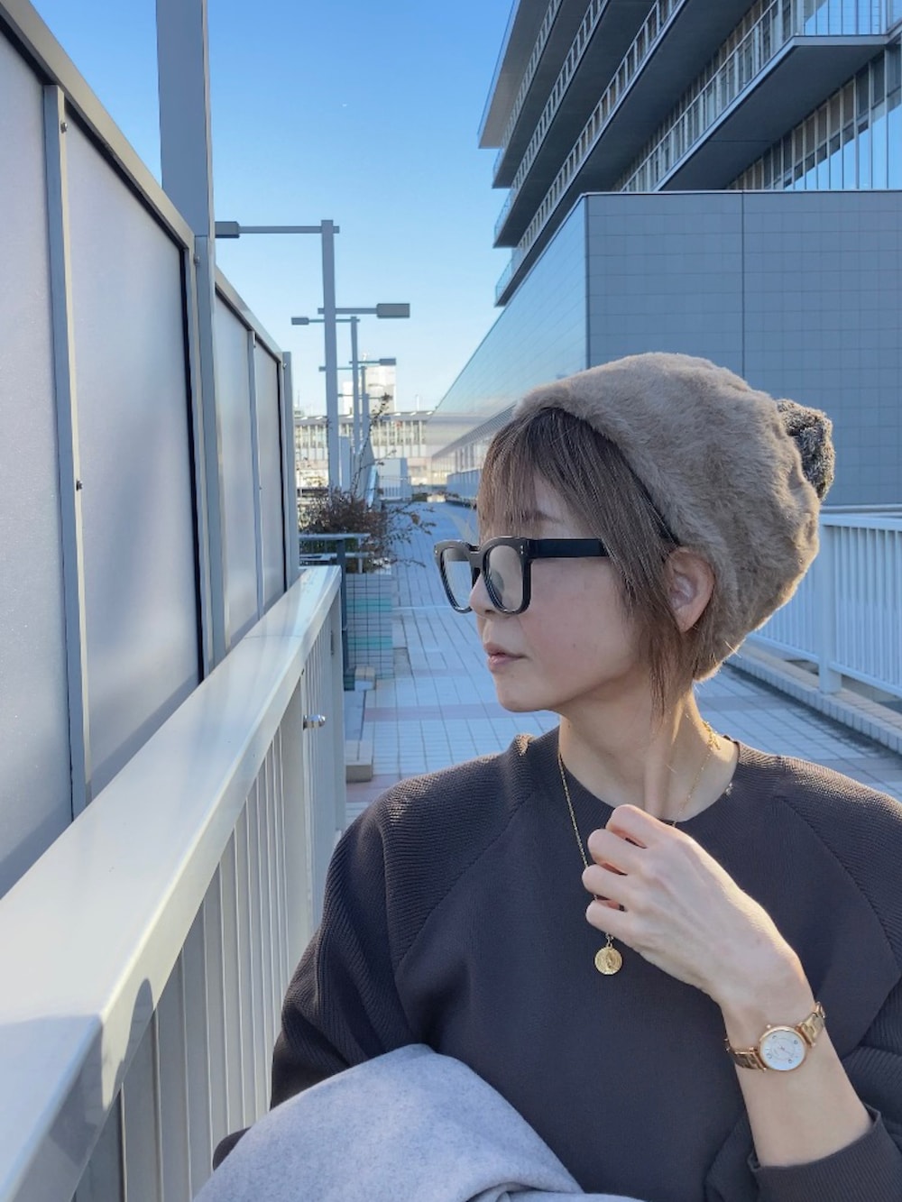 ベージュ系のノーカラーコート、ブラウン系のニット/セーター、ブラウン系のパンツを着用したレディースの秋コーディネートの2枚目の写真