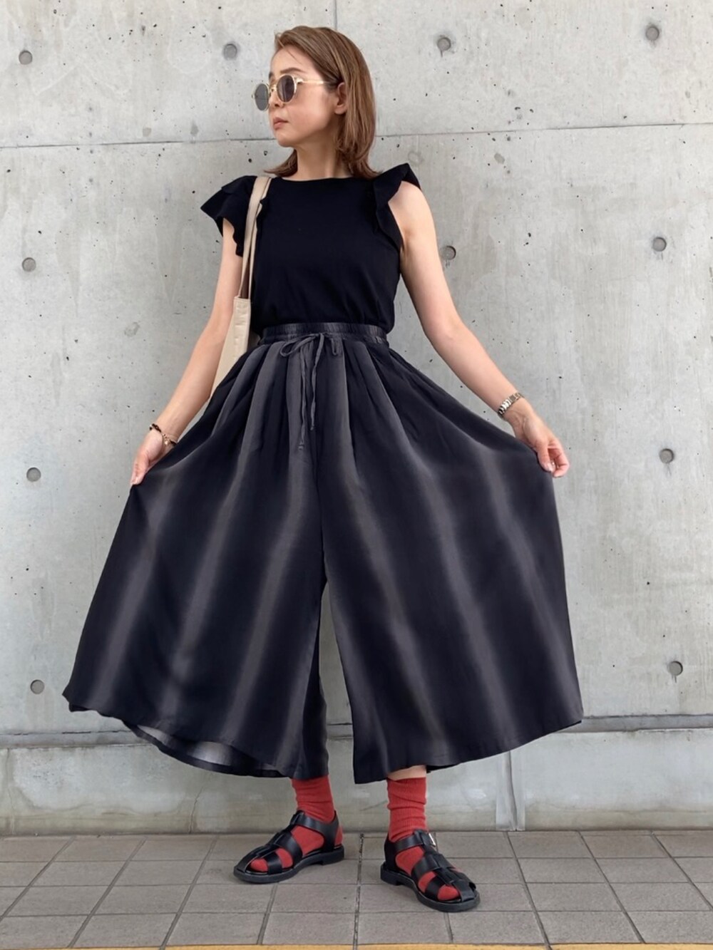 グレー系のパンツ、ブラック系のニット/セーター、ブラック系のサンダルを着用したレディースの春コーディネートの4枚目の写真