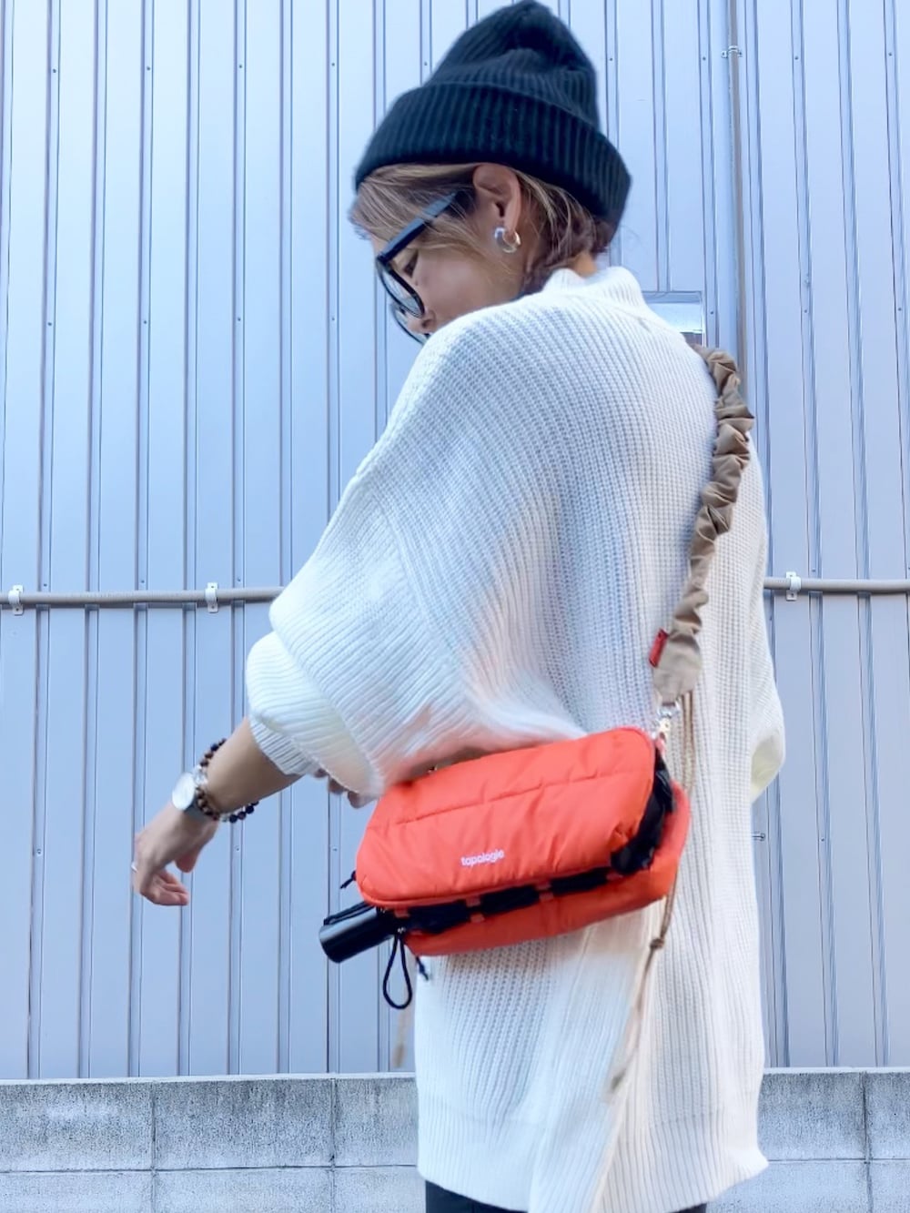 ホワイト系のニット/セーター、オレンジ系のショルダーバッグ、ブラック系のシューズを着用したレディースの秋コーディネートの3枚目の写真