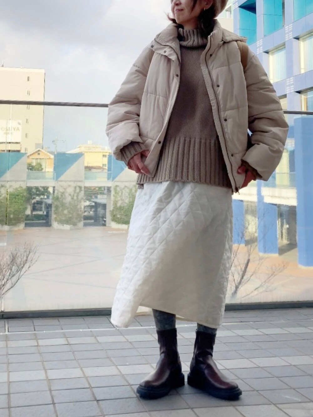 ホワイト系のダウンジャケット/コート、ベージュ系のニット/セーター、ホワイト系のスカートを着用したレディースの冬コーディネートの2枚目の写真