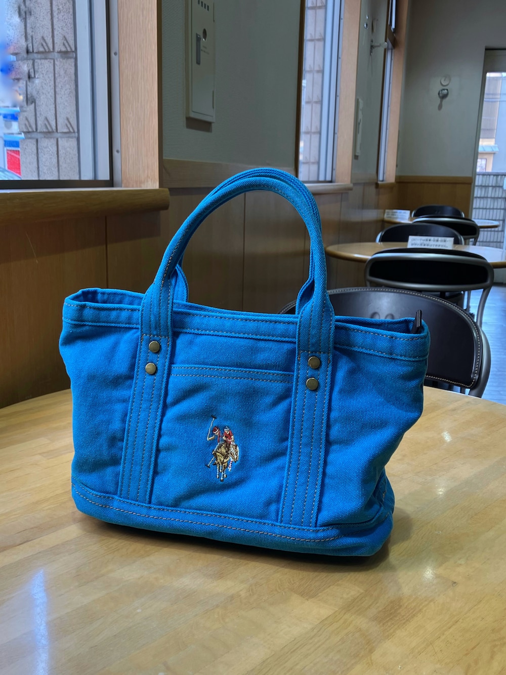 ブルー系のトートバッグ、ブラック系のワンピース、グレー系のベストを着用したレディースの冬コーディネートの2枚目の写真