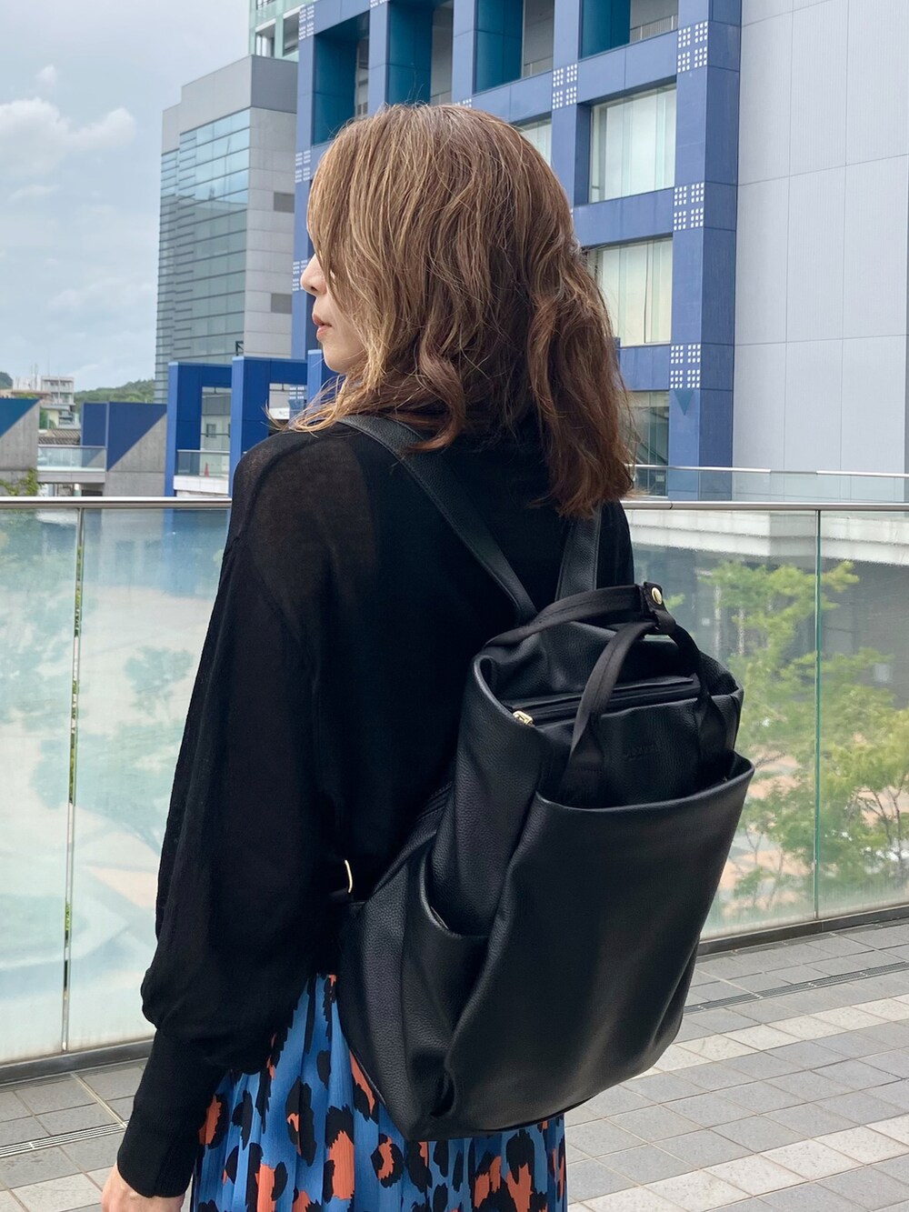 ブルー系のスカート、ブラック系のカーディガン/ボレロ、ブラック系のバックパック/リュックを着用したレディースの秋コーディネートの2枚目の写真