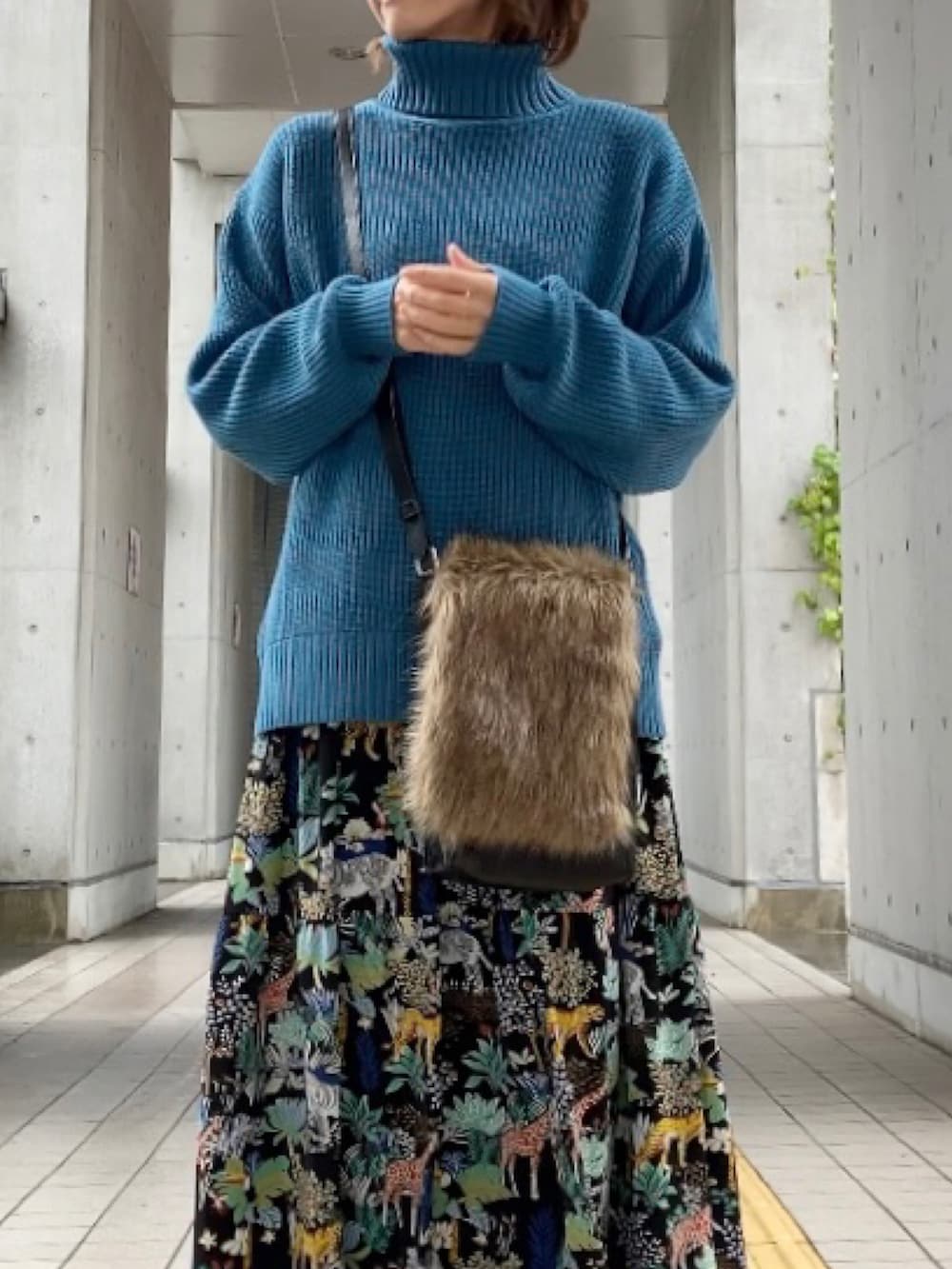 ブルー系のニット/セーター、ブラウン系のショルダーバッグ、ブラック系のワンピースを着用したレディースの秋コーディネートの4枚目の写真