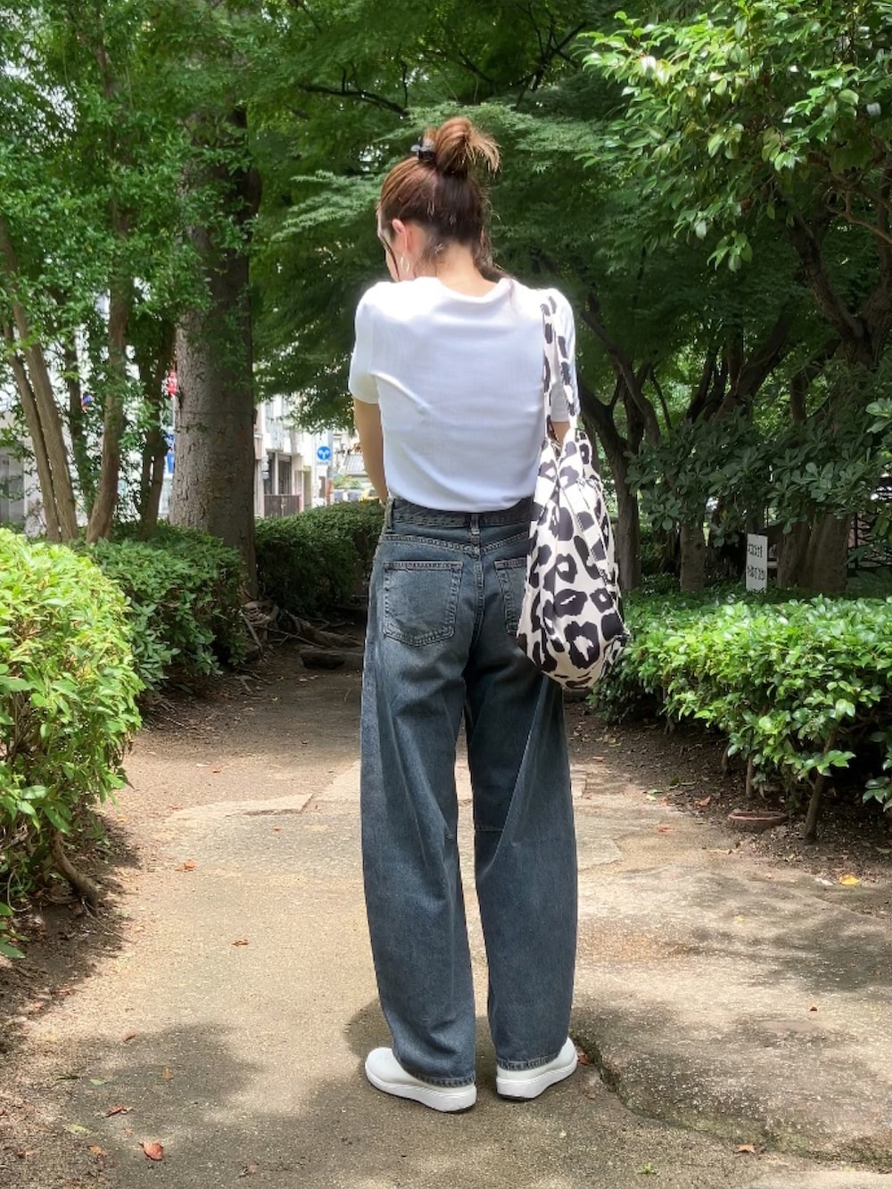 ブルー系のデニムパンツ、ホワイト系のTシャツ/カットソー、ベージュ系のトートバッグを着用したレディースの夏コーディネートの2枚目の写真