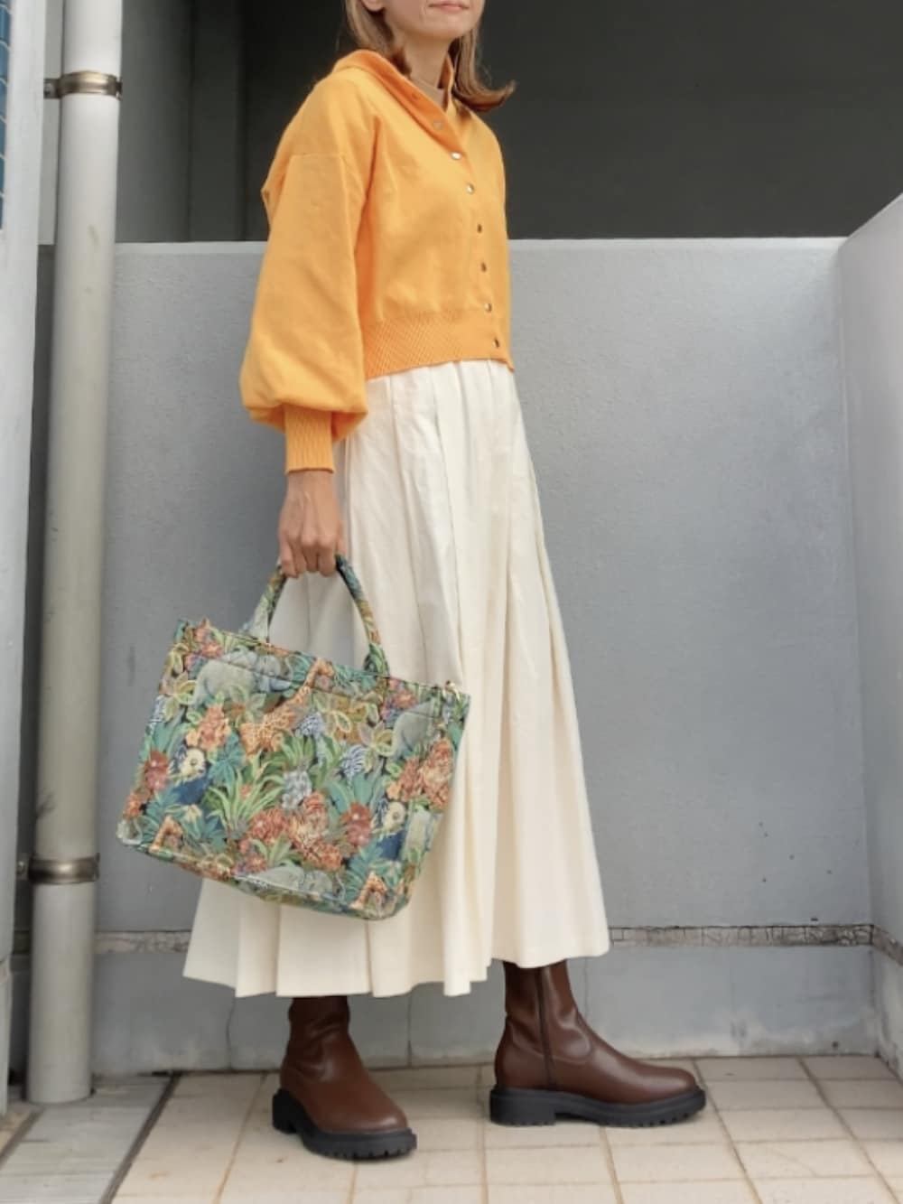 イエロー系のカーディガン/ボレロ、ホワイト系のスカート、その他のトートバッグを着用したレディースの秋コーディネートの2枚目の写真