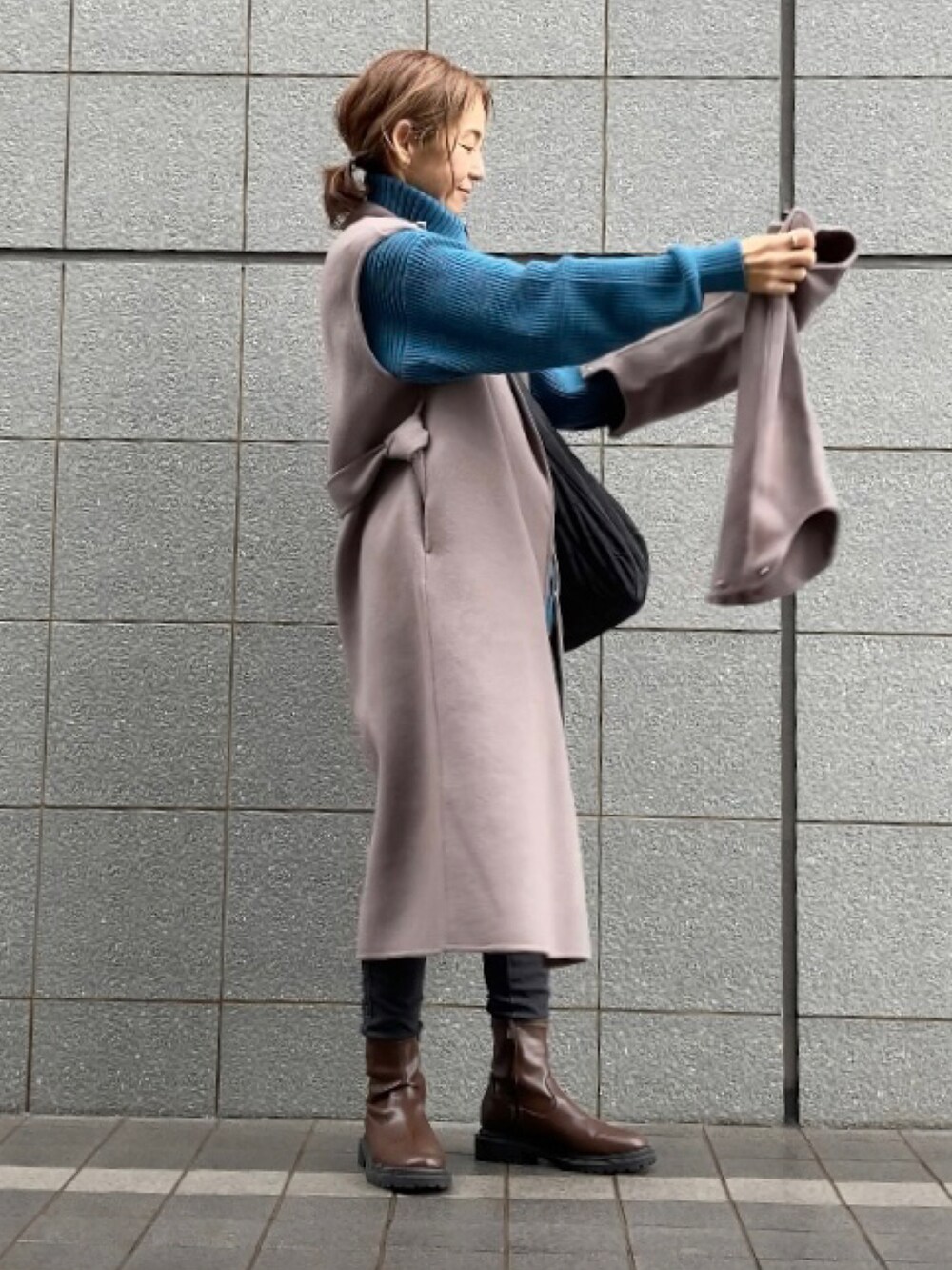 ブラウン系のチェスターコート、ブルー系のニット/セーター、ブラック系のショルダーバッグを着用したレディースの秋コーディネートの3枚目の写真