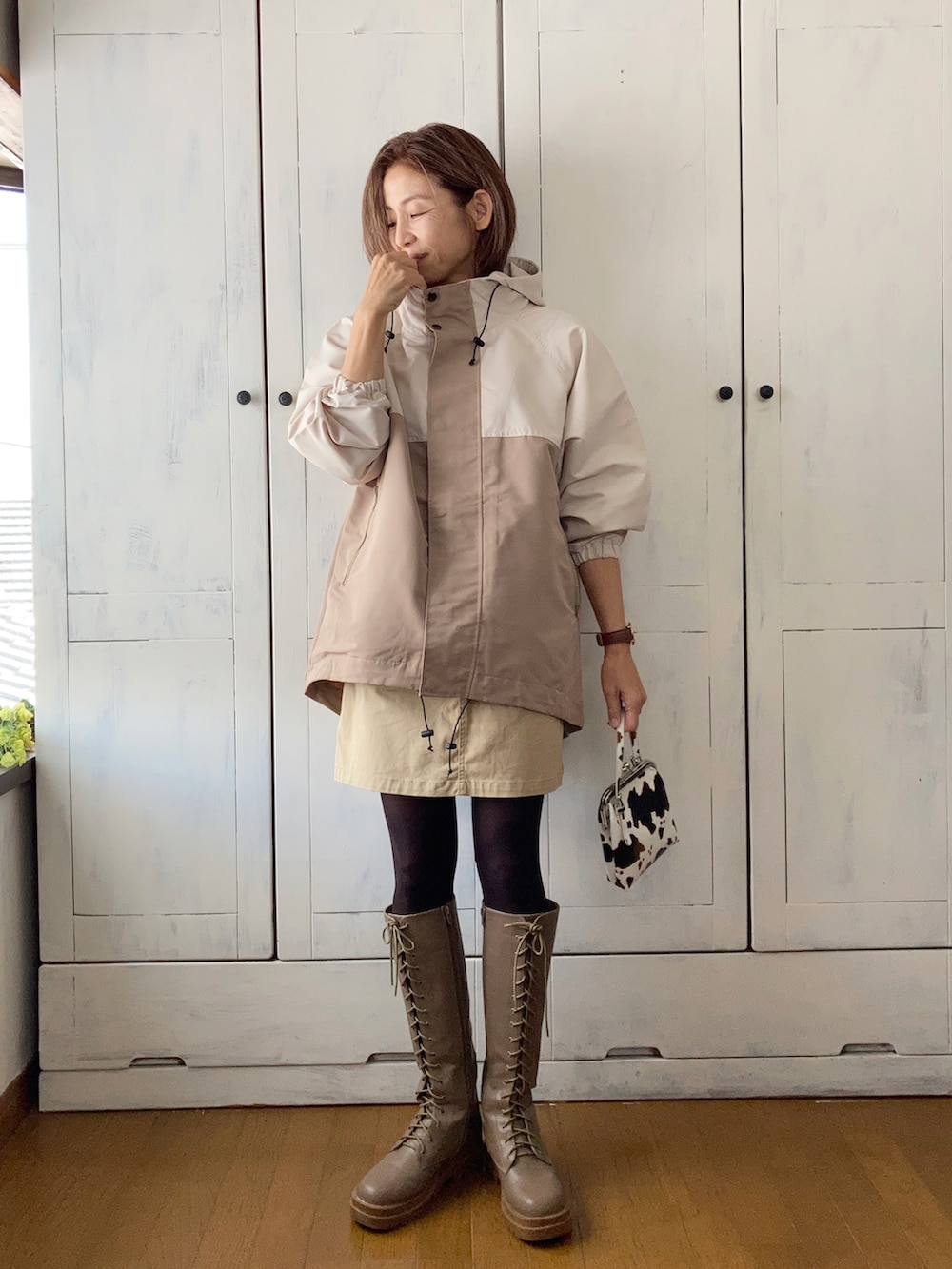 ベージュ系のマウンテンパーカー、ベージュ系のベスト、ベージュ系のスカートを着用したレディースの秋コーディネートの2枚目の写真