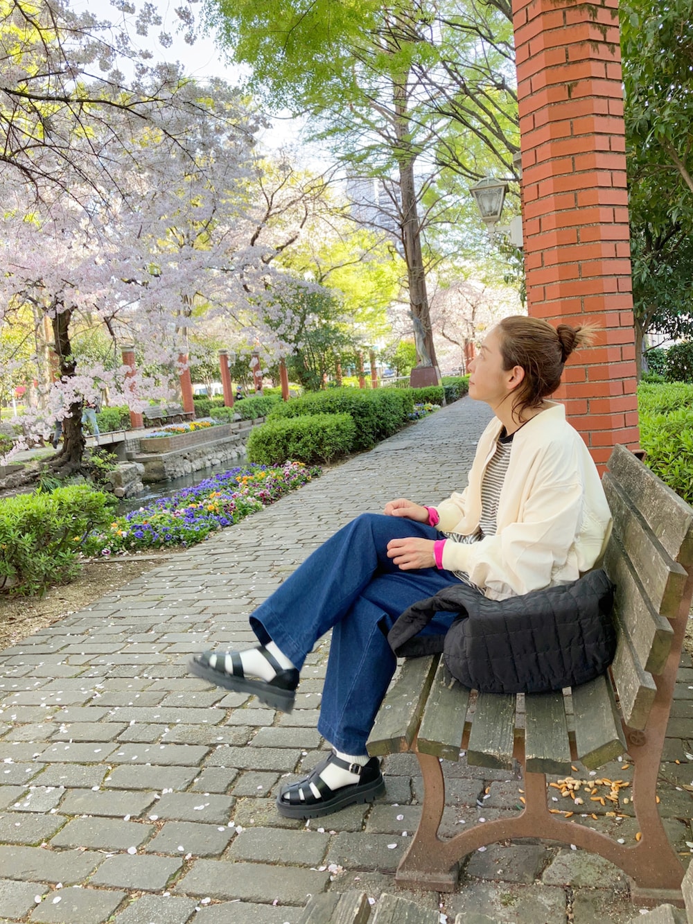 ホワイト系のMA-1、ブラック系のTシャツ/カットソー、ブルー系のデニムパンツを着用したレディースの春コーディネートの4枚目の写真