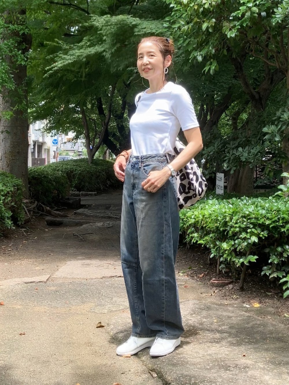 ブルー系のデニムパンツ、ホワイト系のTシャツ/カットソー、ベージュ系のトートバッグを着用したレディースの夏コーディネートの3枚目の写真