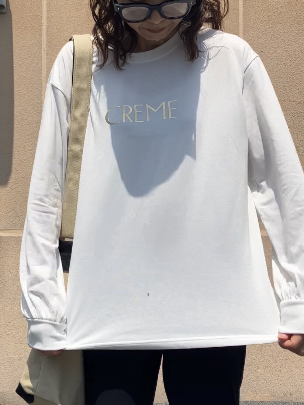 ホワイト系のTシャツ/カットソー、ブラック系のパンツ、ベージュ系のトートバッグを着用したレディースの夏コーディネートの2枚目の写真