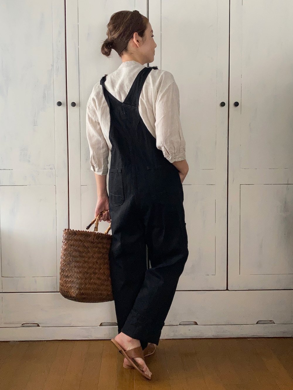 ブラック系のサロペット/オーバーオール、ベージュ系のチュニック、ブラウン系のかごバッグを着用したレディースの春コーディネートの2枚目の写真