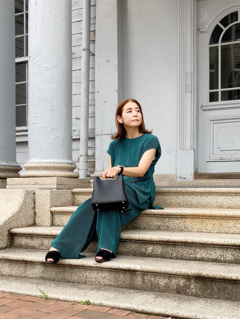 グリーン系のパンツ、ブラック系のハンドバッグ、ブラック系のサンダルを着用したレディースの夏コーディネートの4枚目の写真