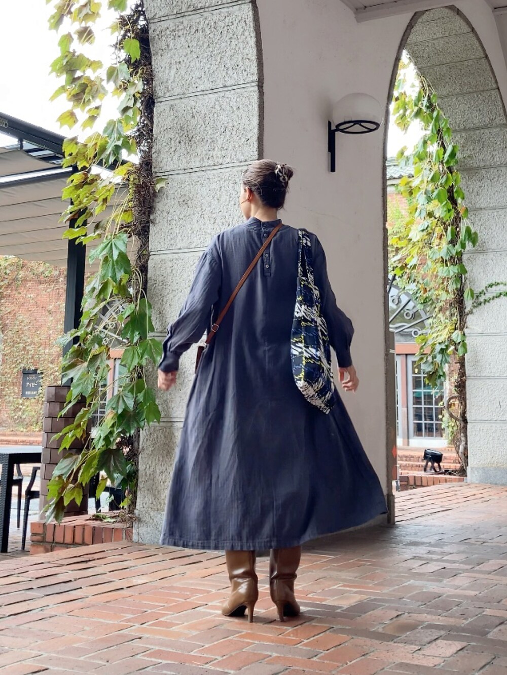 グレー系のワンピース/ドレス、ブラウン系のクラッチバッグ、イエロー系のブーツを着用したレディースの秋コーディネートの4枚目の写真