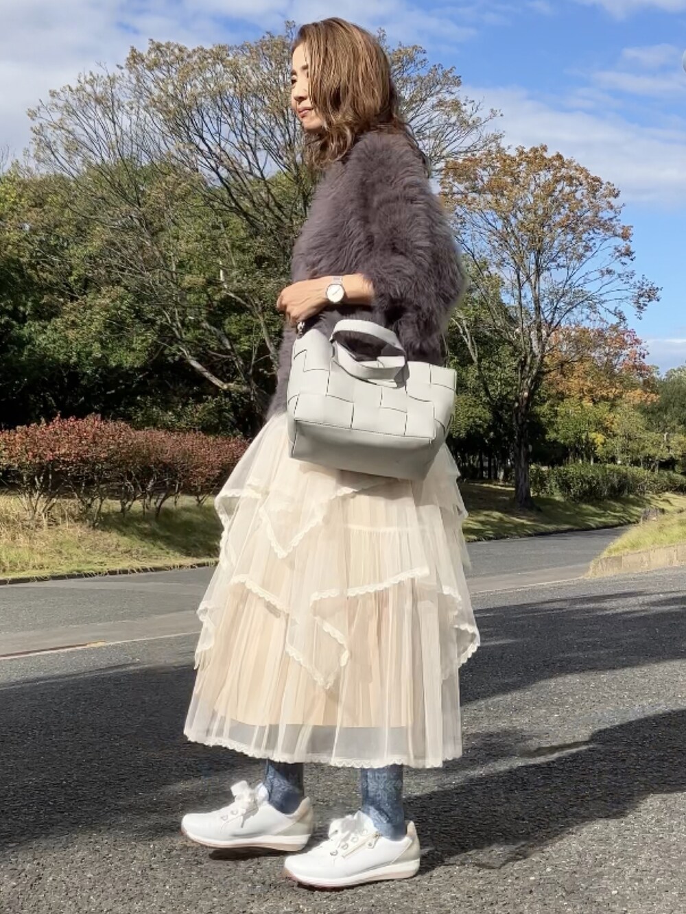 ベージュ系のスカート、グレー系のニット/セーター、グレー系のハンドバッグを着用したレディースの秋コーディネートの3枚目の写真