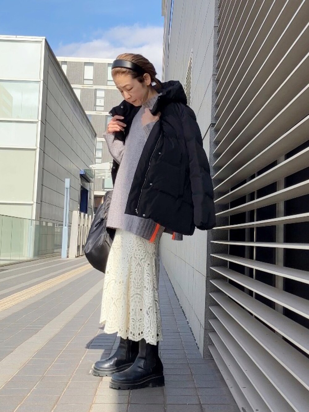 グレー系のニット/セーター、ホワイト系のスカート、ブラック系のブーツを着用したレディースの冬コーディネートの4枚目の写真