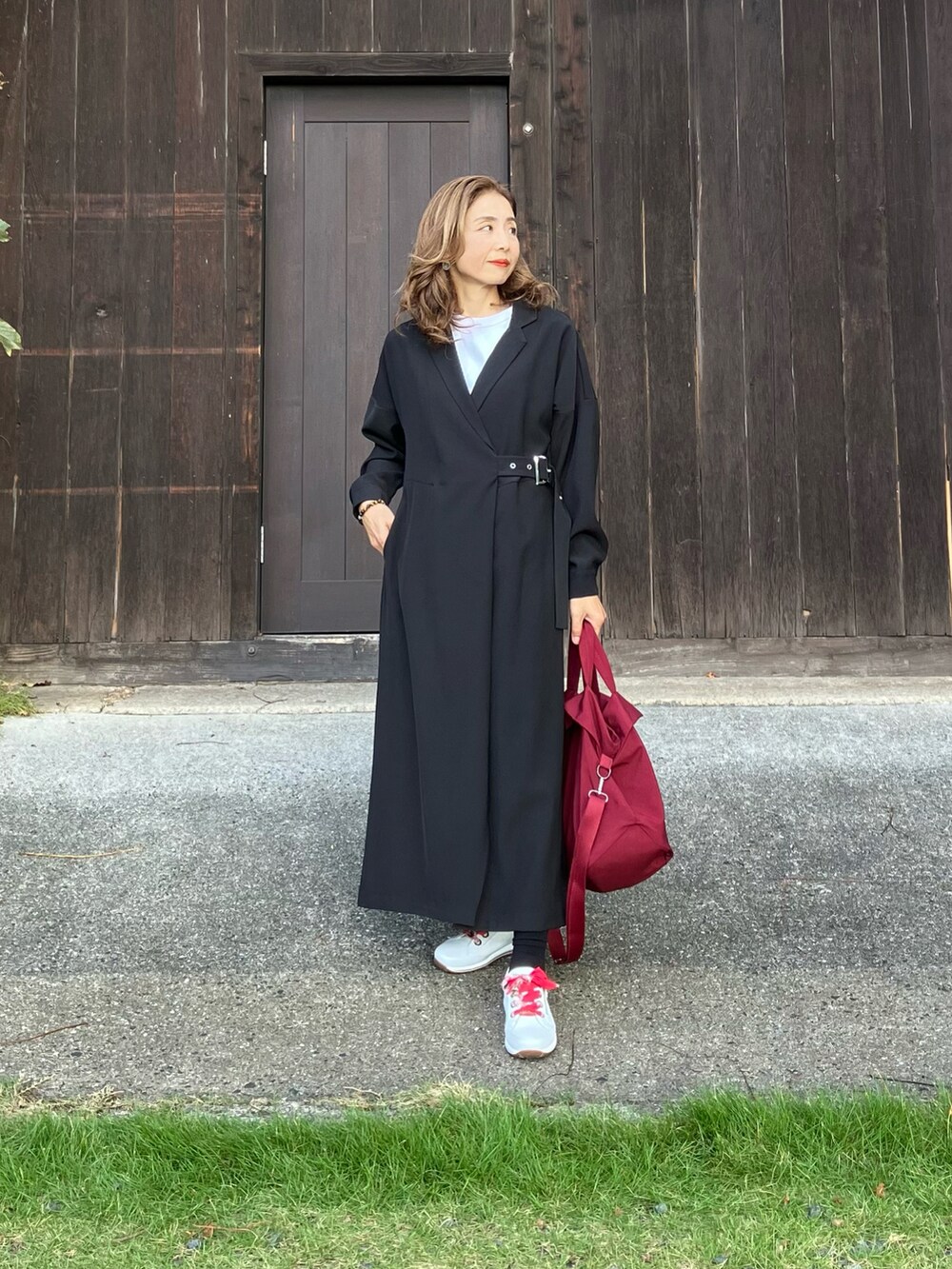 ホワイト系のスニーカー、レッド系のボストンバッグ、ブラック系のシャツワンピースを着用したレディースの秋コーディネートの2枚目の写真