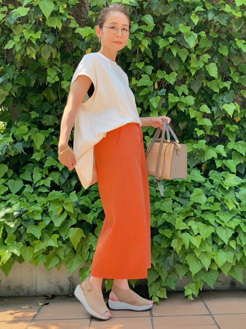 ホワイト系のTシャツ/カットソー、オレンジ系のスカート、グレー系のハンドバッグを着用したレディースの春コーディネートの2枚目の写真